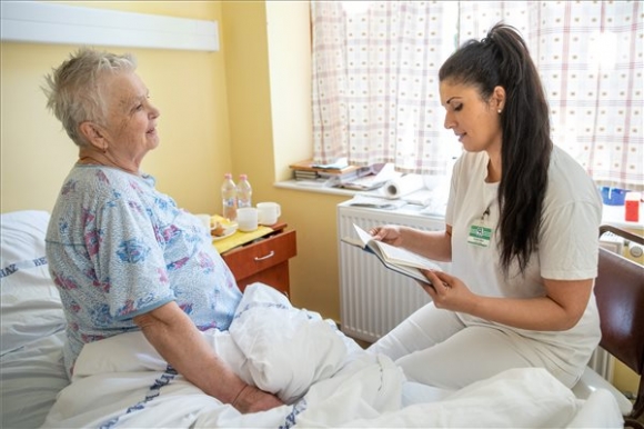 Sztojka Edina, a gyulai kórháza ápolója olvas egy betegnek a gyulai Pándy Kálmán kórház hospice osztályán 2019. április 25-én. MTI/Rosta Tibor