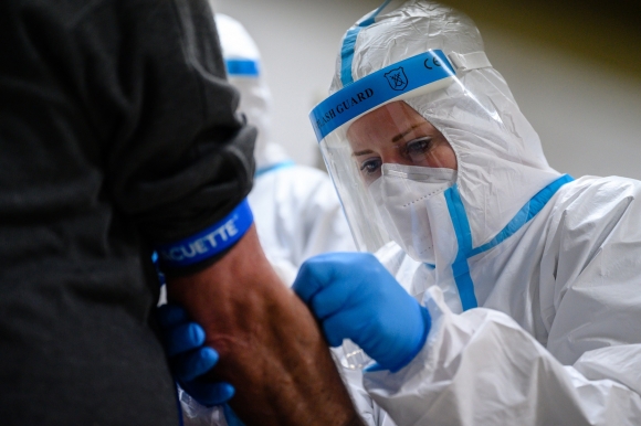 A koronavírus-teszthez vért vesz egy férfitől a Semmelweis Egyetem szakembere a székesfehérvári Alba Regia Sportcsarnok Sportorvosi rendelőjében 2020. május 12-én. Fotó: MTI/Vasvári Tamás