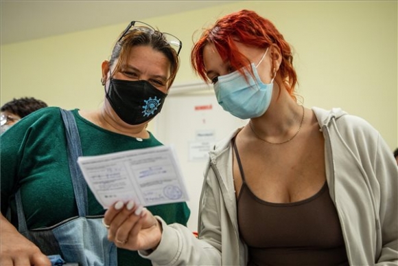 Egy nő lányával nézi az oltási igazolást, miután beoltották a német-amerikai fejlesztésű Pfizer-BioNTech koronavírus elleni oltóanyag, a Comirnaty-vakcina második adagjával a békéscsabai Réthy Pál kórházban 2021. szeptember 20-án (MTI/Rosta Tibor)